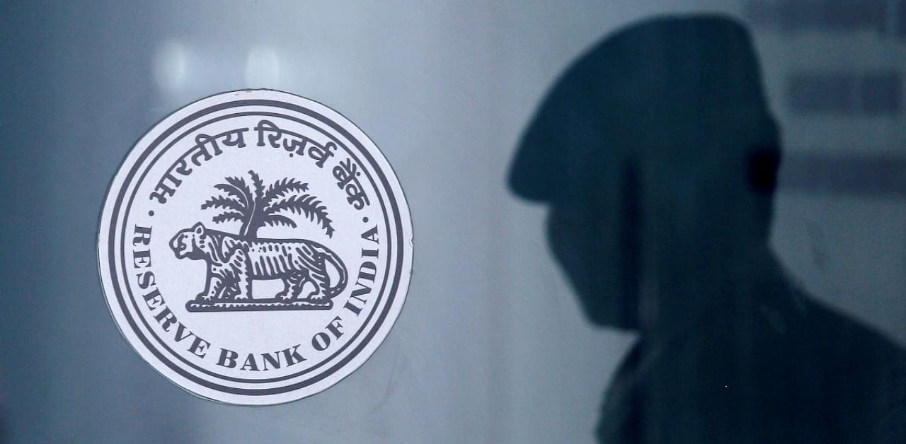 A security guard's reflection is seen next to the logo of the Reserve Bank Of India (RBI) at the RBI headquarters in Mumbai, India. Credit: Reuters