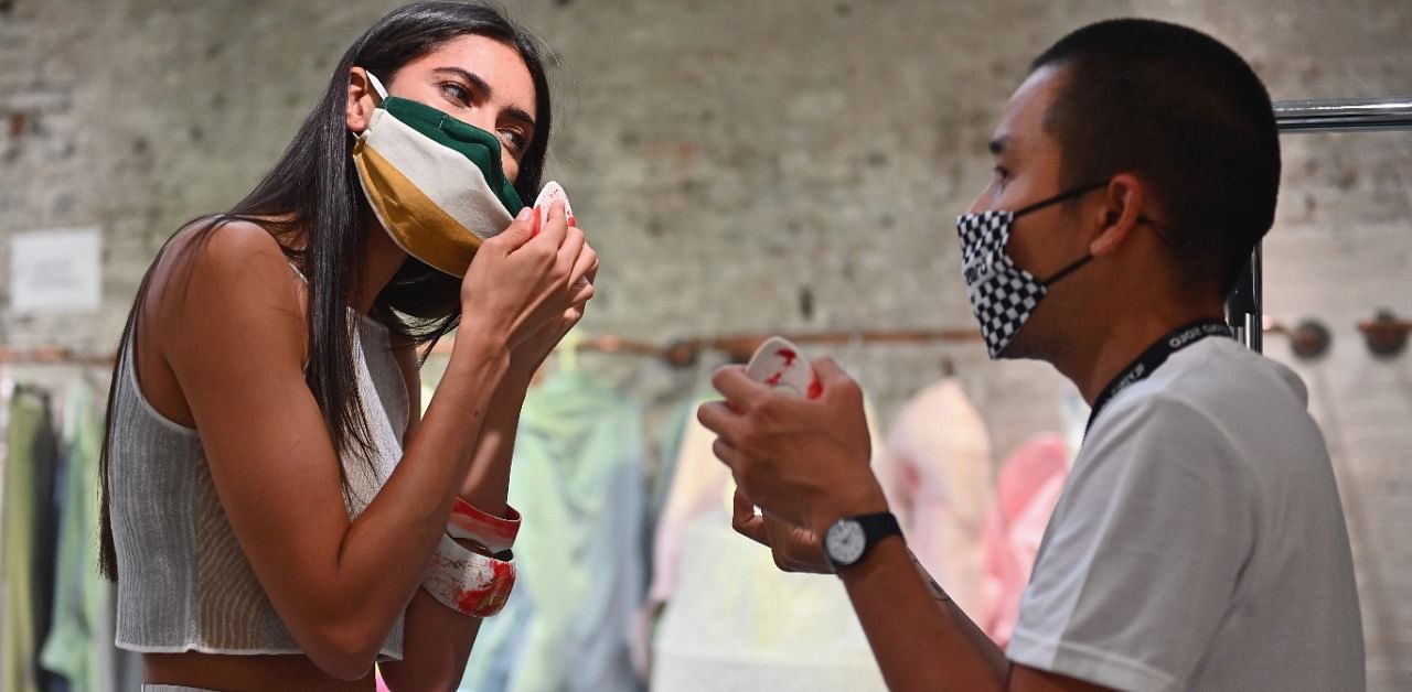 A model takes off her face mask to get fitted for the Flying Solo runway show featuring a collective of local designers on September 11, 2020 New York City. Credit: AFP