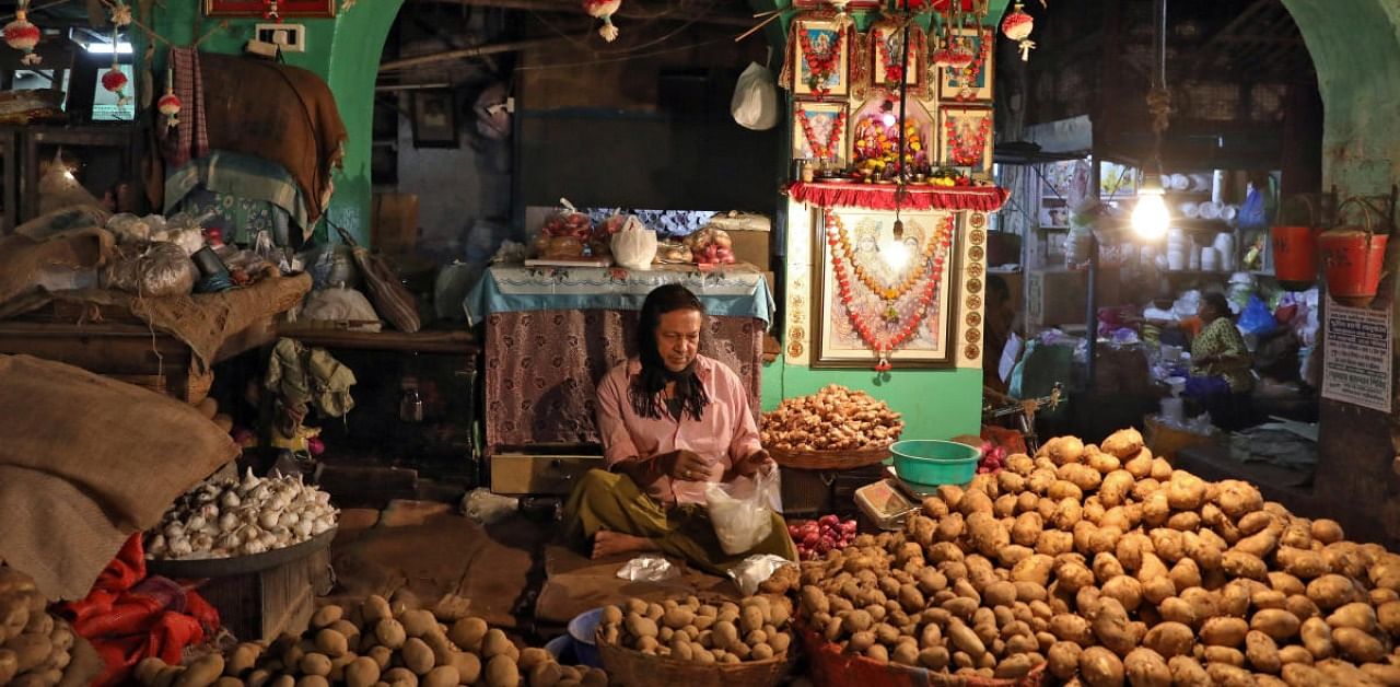 A vendor waits for customers at his shop inside a vegetable market in Kolkata, India. Credit: Reuters