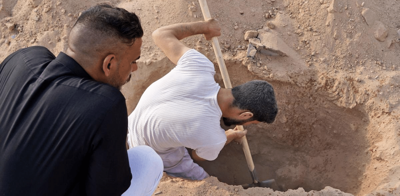 An Iraqi family digs up the corpse of a relative, who died of the novel coronavirus, at a coronavirus cemetery in a plot of desert outside the Shiite holy city of Najaf to be transferred to a family cemetery for reburial. Credit: AFP Photo