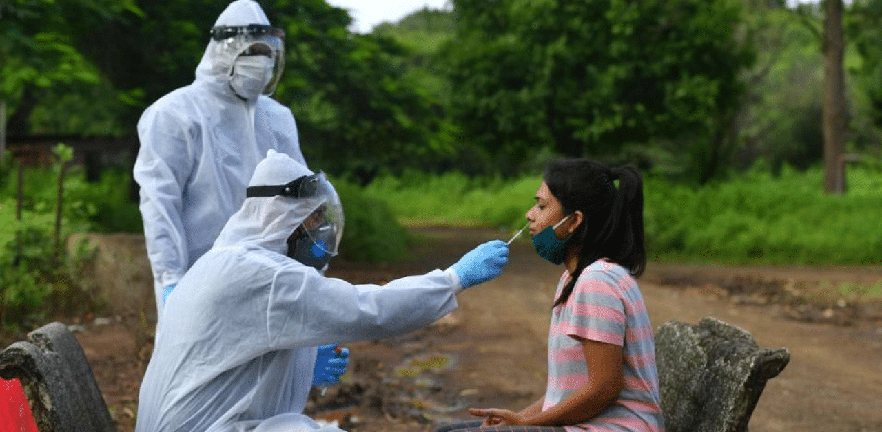 Medical staff wearing Personal Protective Equipment (PPE) take a nasal swab sample from a woman during a Covid-19. Credit: AFP