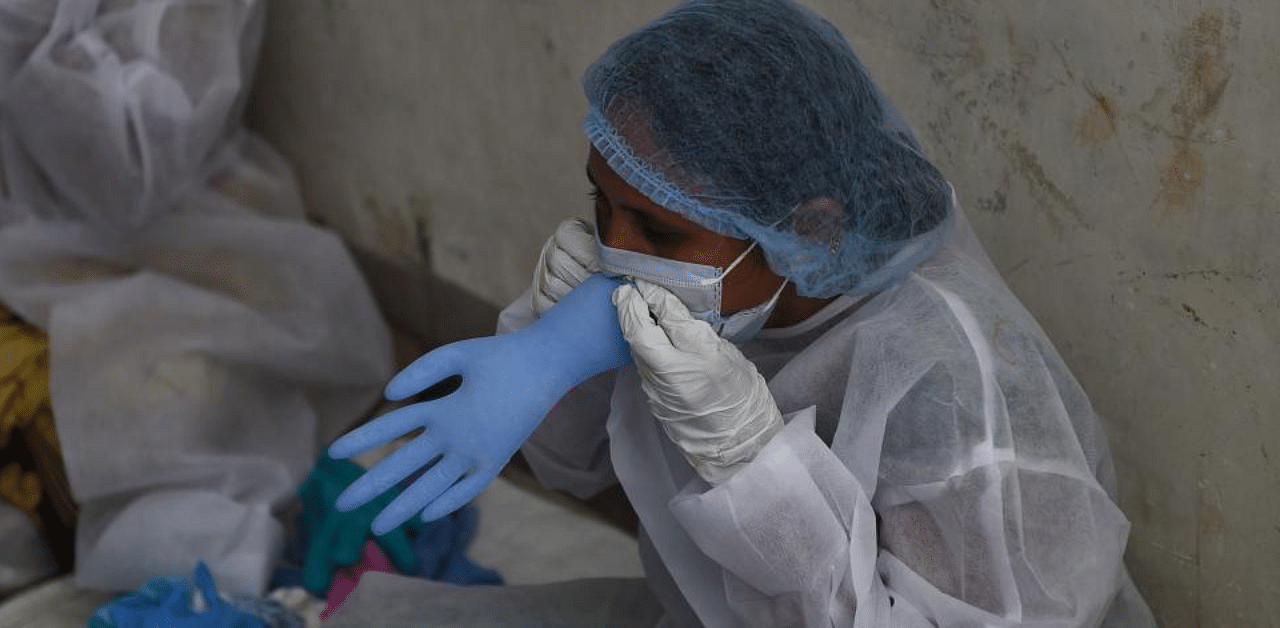 A worker wearing a Personal Protective Equipment (PPE) checks the quality of a hand glove at a Stacee Multicare workshop, on the outskirts of Ahmedabad on September 7, 2020. Credit: AFP Photo