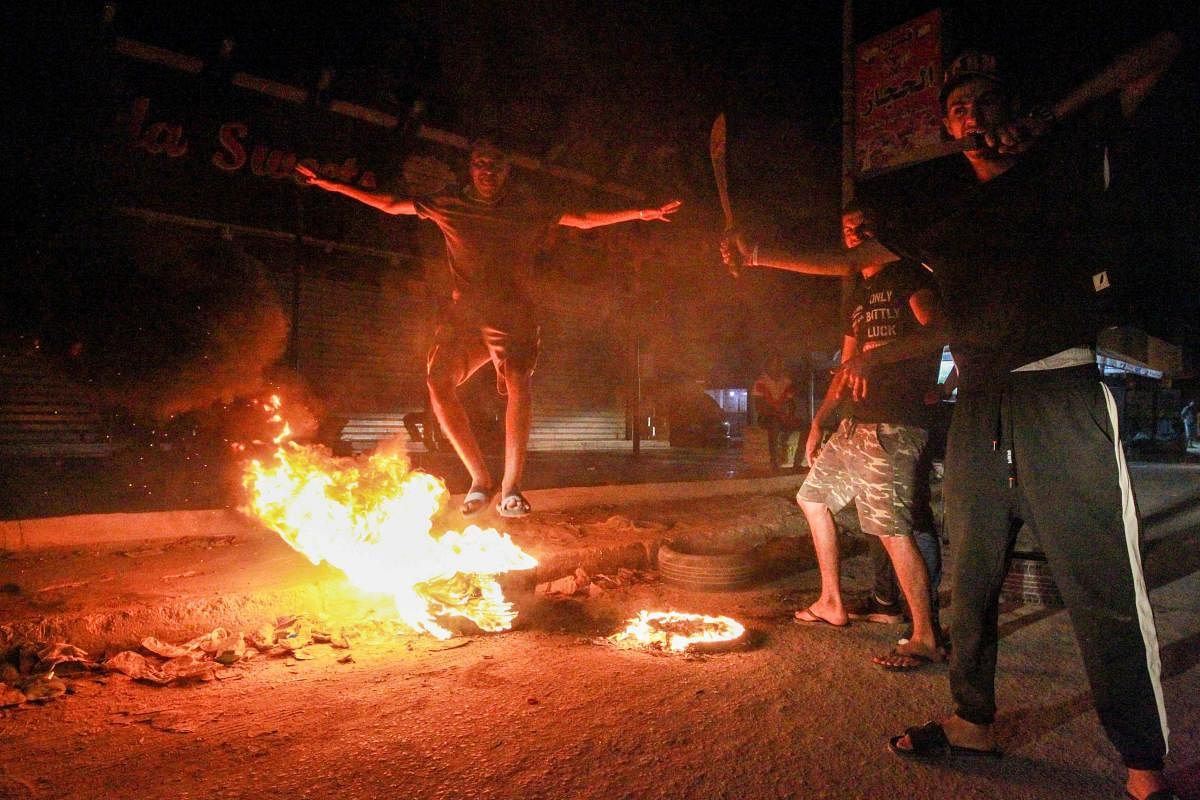 Libyan youth block a road with burning tyres in Libya's eastern coastal city of Benghazi. Credit: AFP