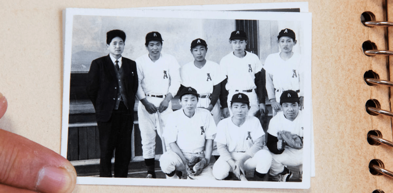 Masashi Yuri, a classmate of Japan's Chief Cabinet Secretary Yoshihide Suga, shows a photo of Suga (back row, R), taken when he was around fourteen years old, from a collection of photos at Yuri's home in Yuzawa, Akita Prefecture, Japan. Credit: Reuters Photo