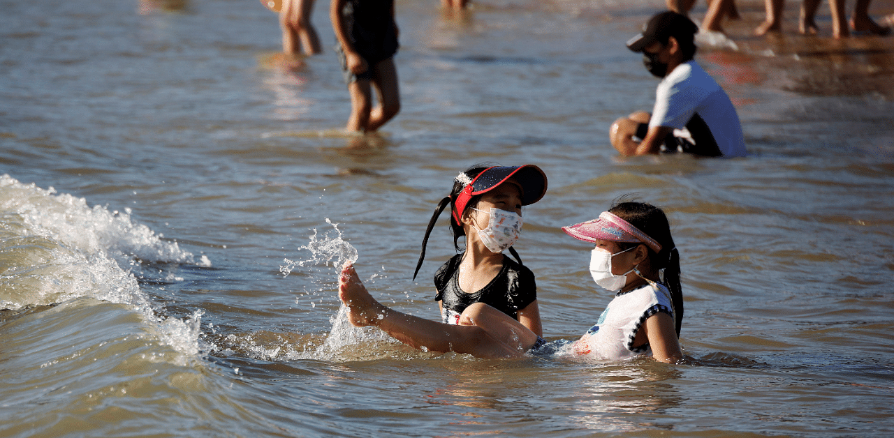 Children wearing protective masks enjoy a late summer day at the beach amid the Covid-19 pandemic in Incheon, South Korea. Credit: Reuters Photo