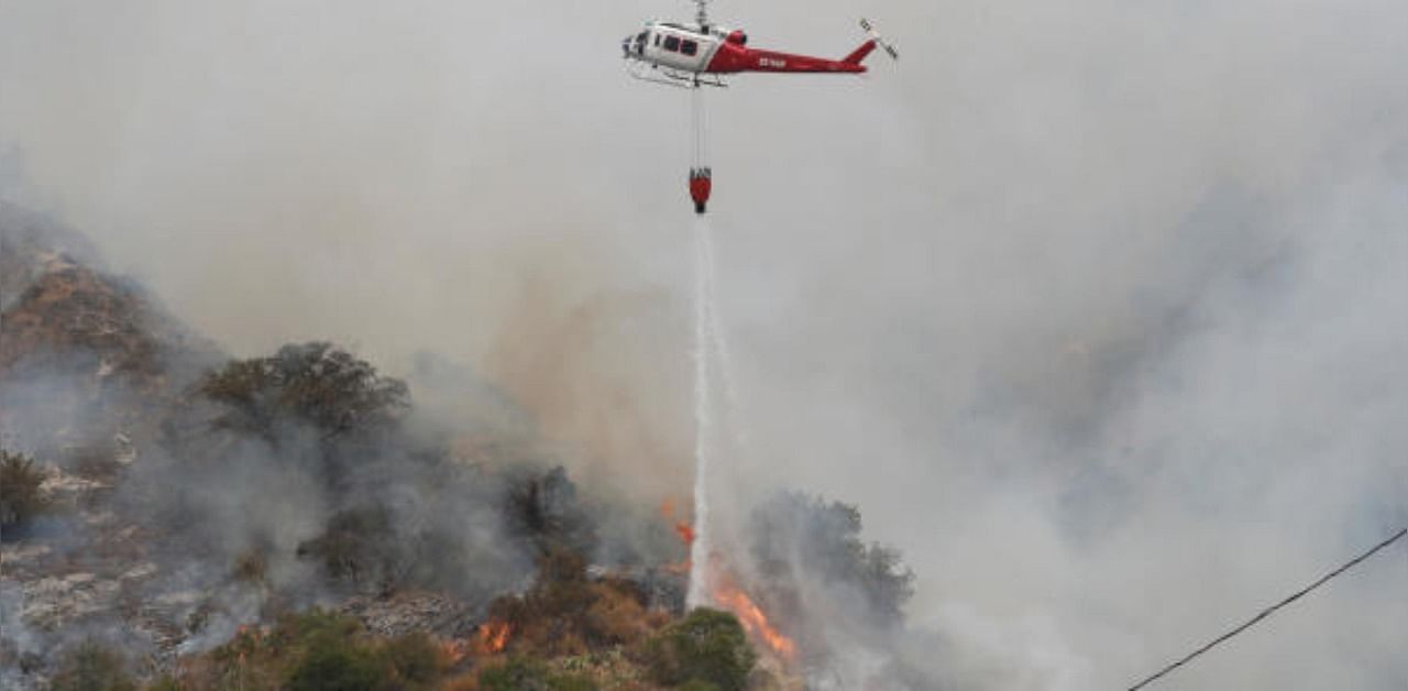 A helicopter drops water to help extinguish the Bobcat Fire, in Arcadia, California, U.S. Credit: Reuters Photo