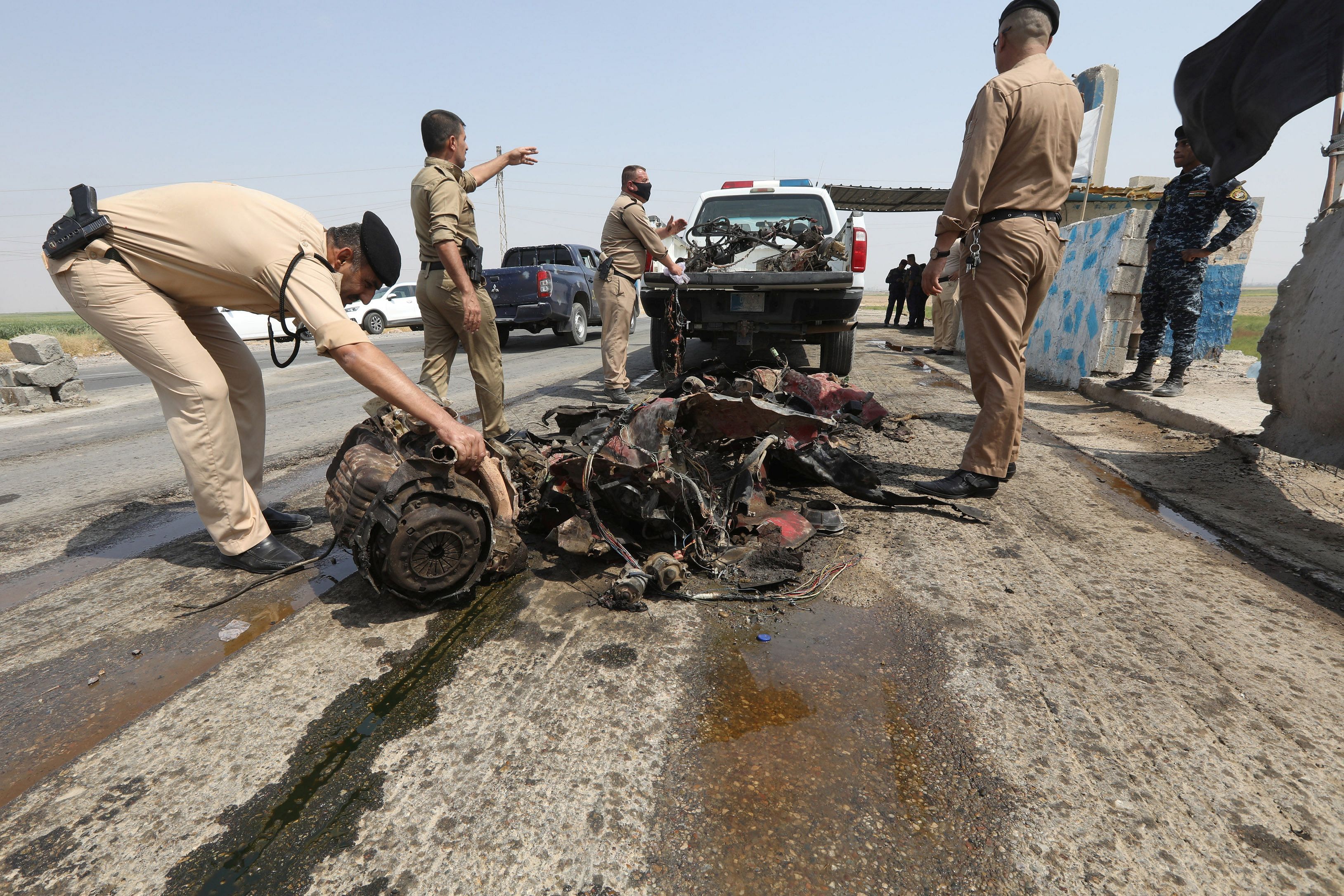 A member of Iraqi security forces checks the remains of a vehicle at the site of a car bomb at a police checkpoint on the road between Kirkuk and Salahuddin province, Iraq. Credits: Reuters Photo