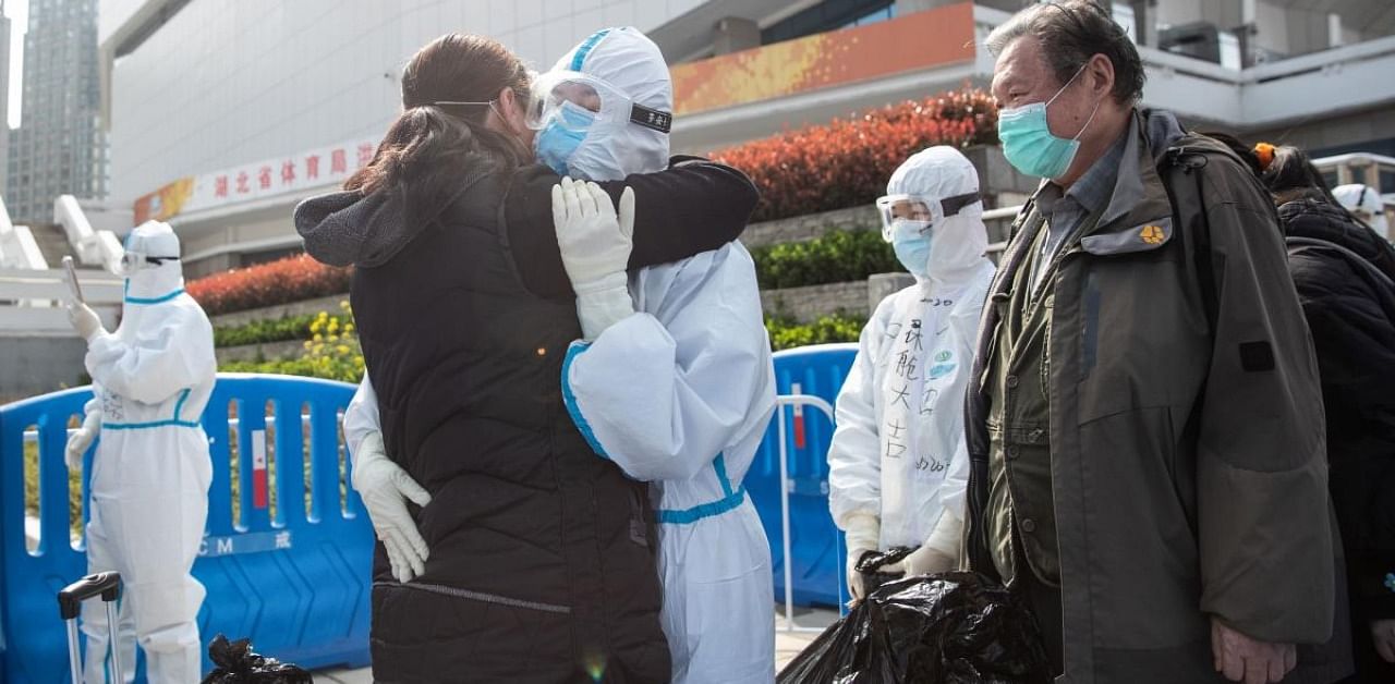 A woman who recovered from the Covid-19 hugging a medical staff member before leaving a temporary hospital set up to treat people with the COVID-19 coronavirus in Wuhan. Credit: AFP