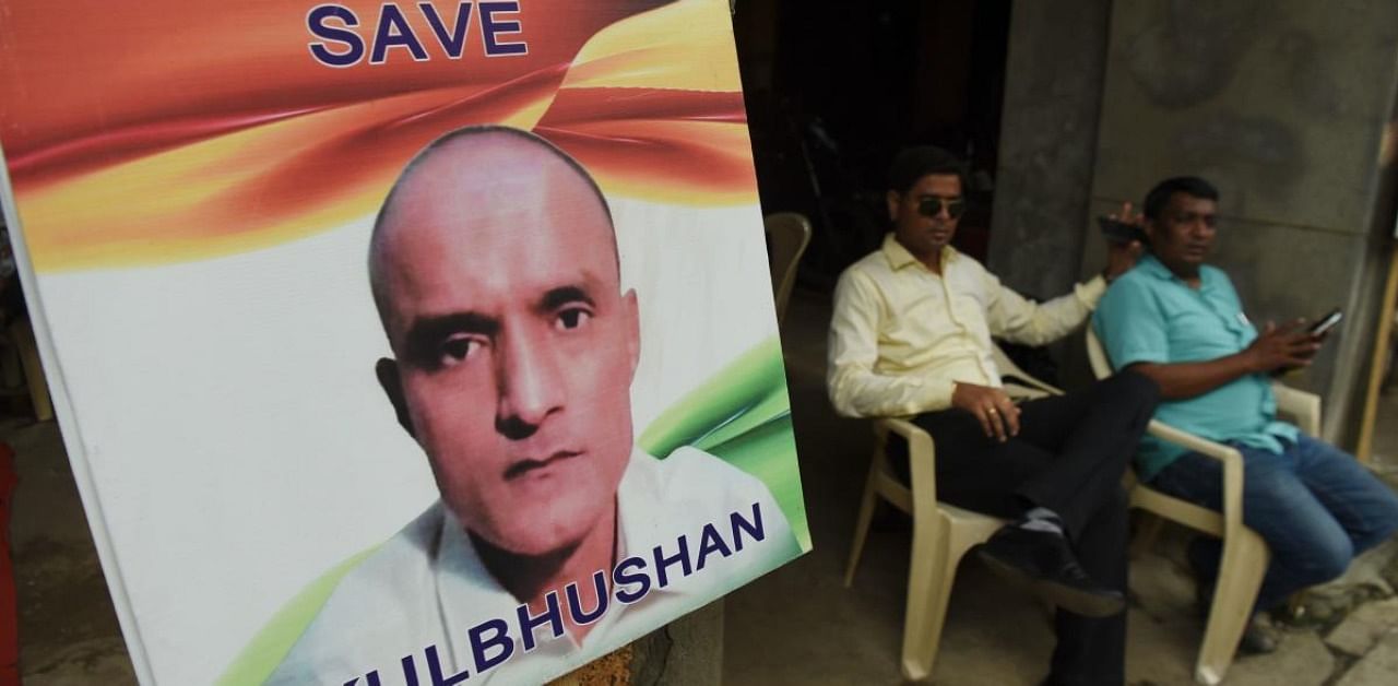 Indian residents sit next to a placard with the picture of Kulbhushan Jadhav. Credit: AFP