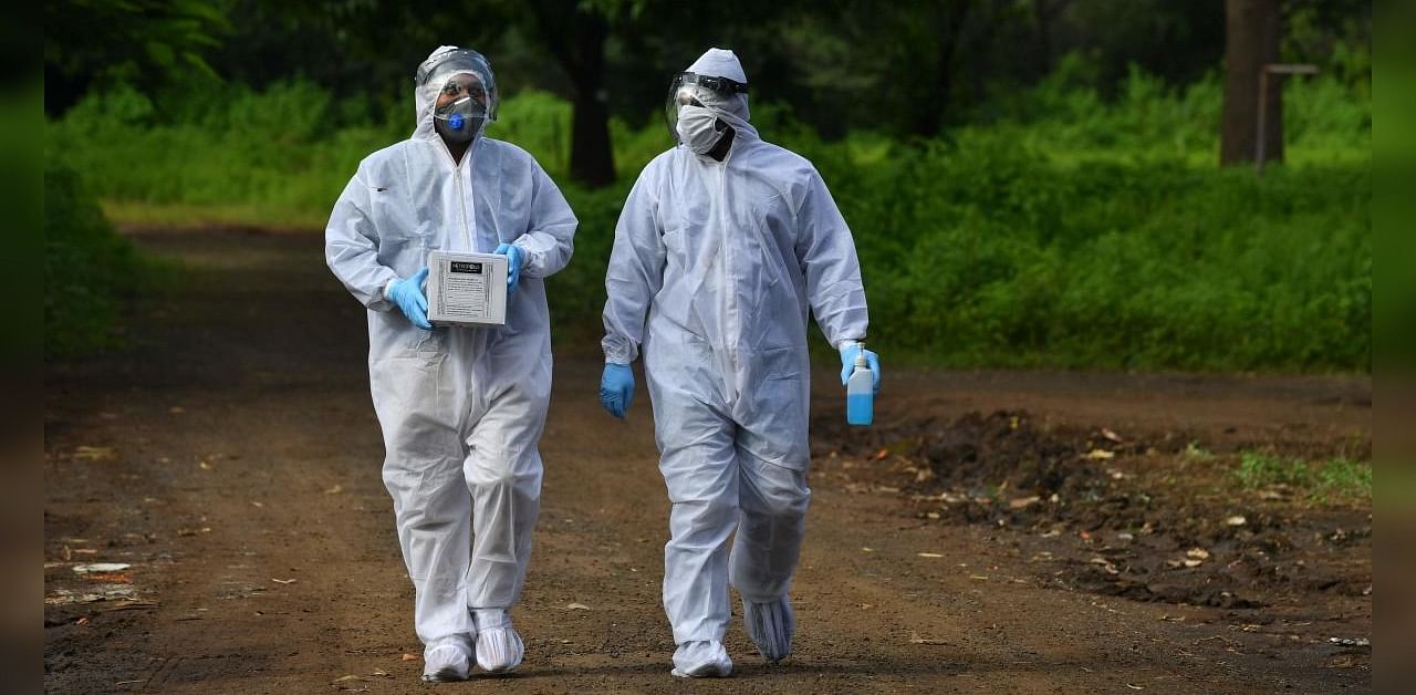 Medical staff wearing Personal Protective Equipment (PPE) carry nasal swab samples during a Covid-19 screening outside a quarantine centre, in Nashik on September 13, 2020. Credit: AFP Photo