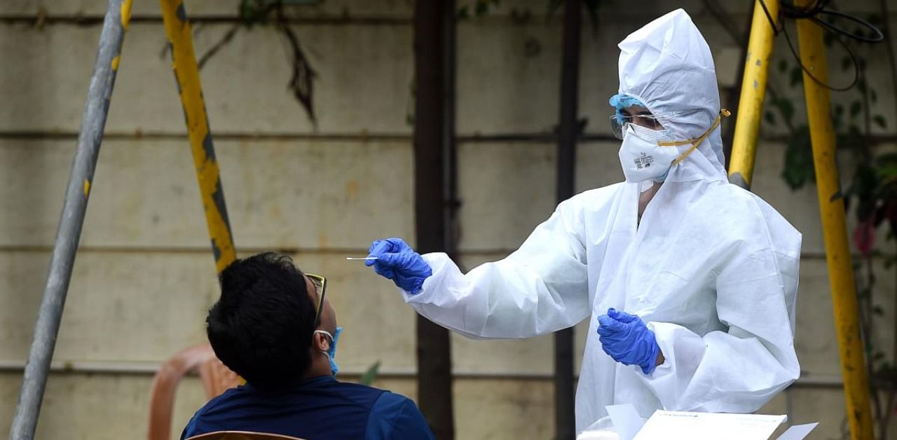 A medical staff wearing Personal Protective Equipment (PPE) takes a nasal swab sample from a resident for a coronavirus test. Credit: AFP