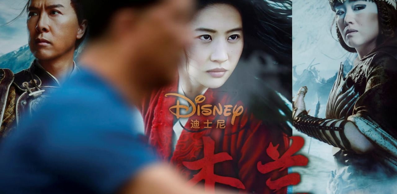 A man rides past an advertisement promoting Disney's movie 'Mulan' at a bus stop in Beijing, China. Credit: Reuters