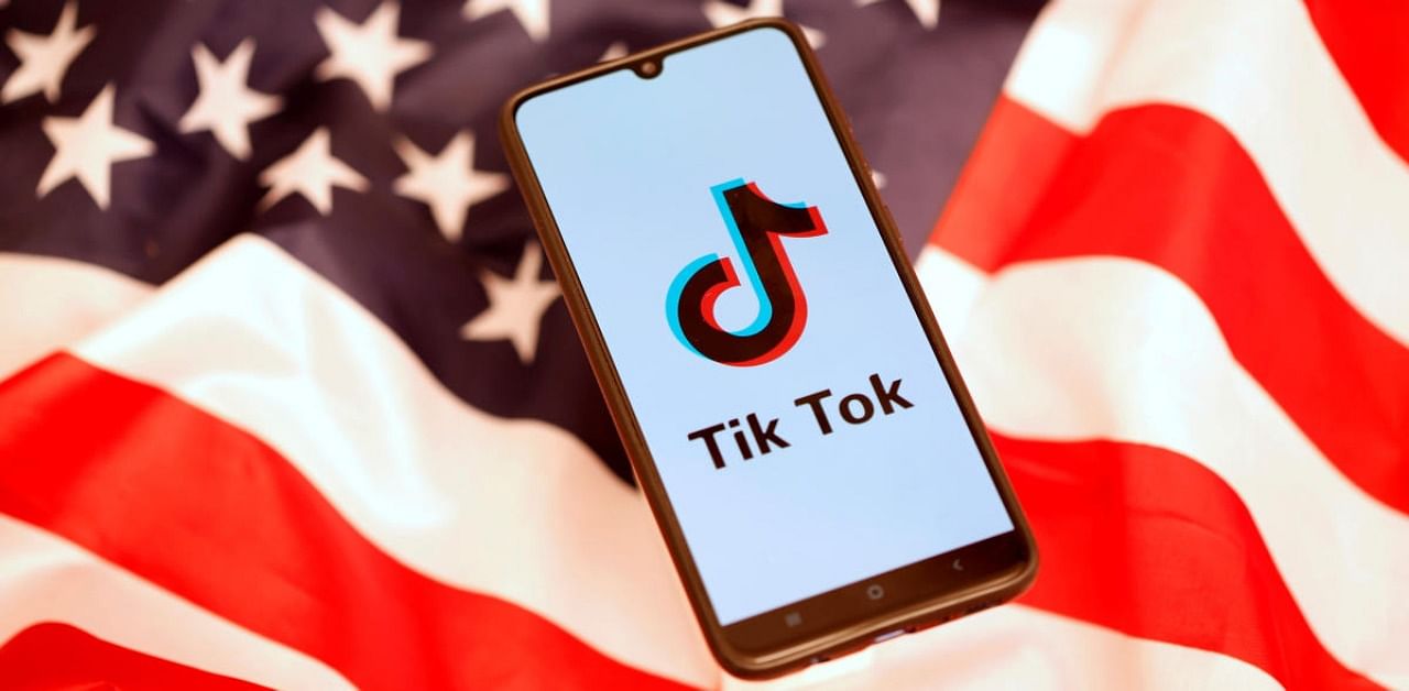 TikTok logo is displayed on the smartphone while standing on the US flag. Credit: Reuters