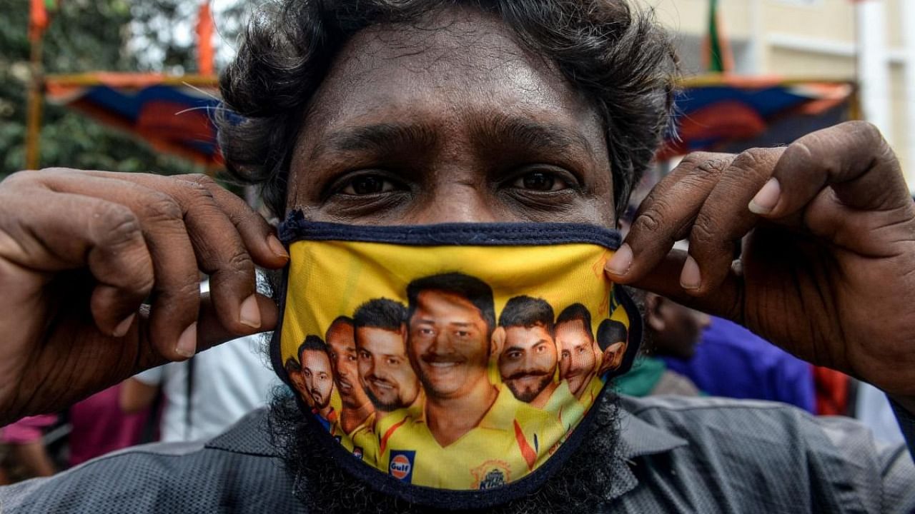 A man shows his facemask decorated with portraits of Chennai Super Kings cricket captain Mahendra Singh Dhoni (C) and other team players as Covid-19 coronavirus cases continue to rise in the country, in Chennai. Credit: AFP