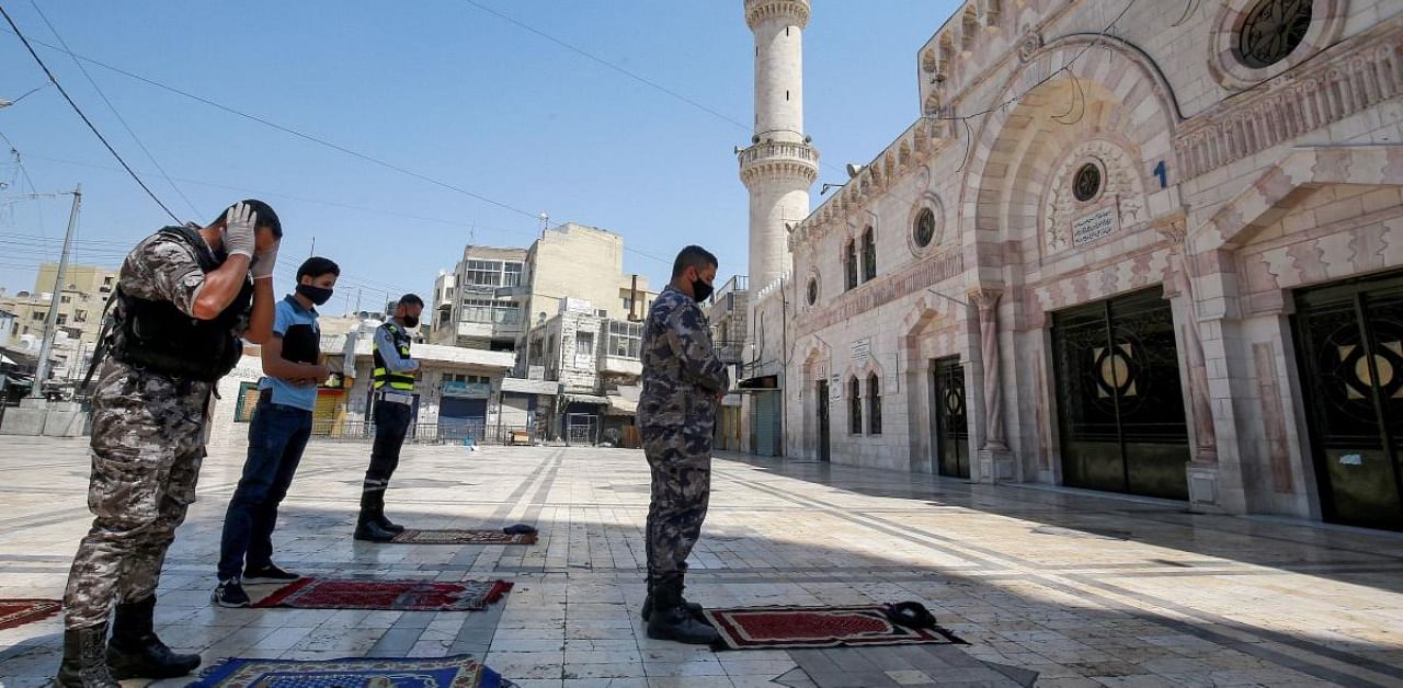 Policemen perform the Muslim Friday prayers outside the Grand Husseini Mosque during a curfew due to the coronavirus pandemic in Jordan's capital Amman. Credit: AFP