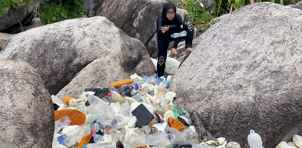 A woman clears trash by the sea at Tioman Island, Pahang, Malaysia. Credit: Reuters