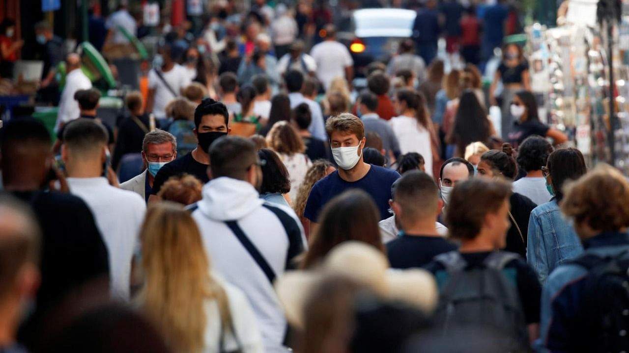 People wearing protective face masks walk in a busy street in Paris as France reinforces mask-wearing in public places as part of efforts to curb a resurgence of the coronavirus disease. Credit: Reuters.