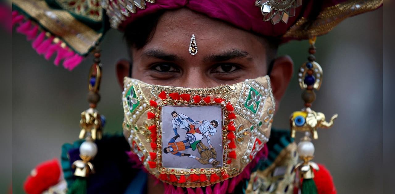 A participant in traditional costume wearing a mask featuring "COVID-19 warriors" as he attends a rehearsal for Garba, a folk dance, ahead of Navratri, a festival during which devotees worship the Hindu goddess Durga and youths dance in traditional costumes, amidst the coronavirus disease outbreak, in Ahmedabad, India, September 18, 2020. Credit: Reuters Photo