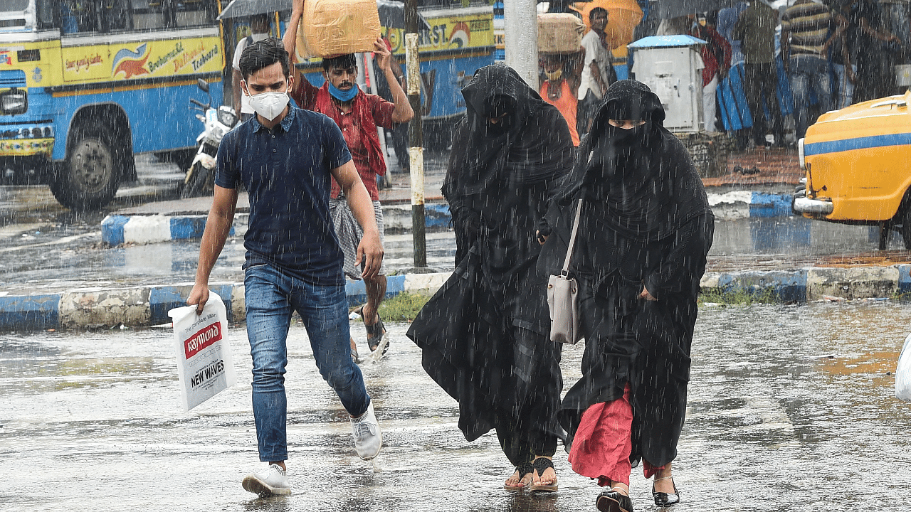 Pedestrians run for shelter across a road during sudden rainfall, in Kolkata. Credits: PTI Photo