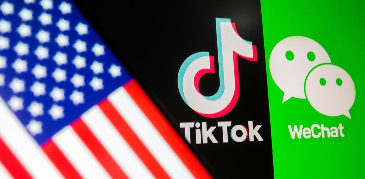 A US flag is seen on a smartphone in front of displayed TikTok and WeChat logo. Credit: Reuters