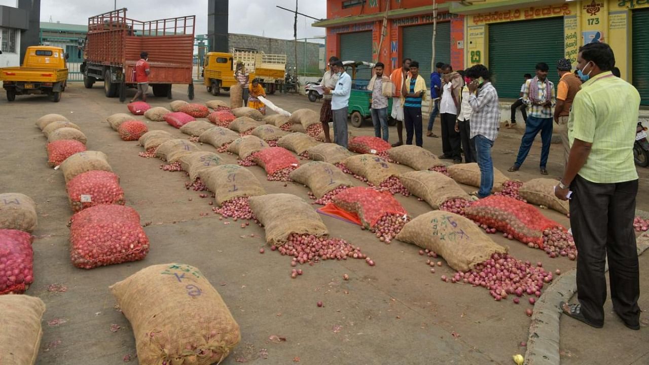 Buyers stand next to sacks of onions during vendor's auction at the Agricultural Produce Marketing Committee (APMC) market yard in Bengaluru. Credit: AFP.