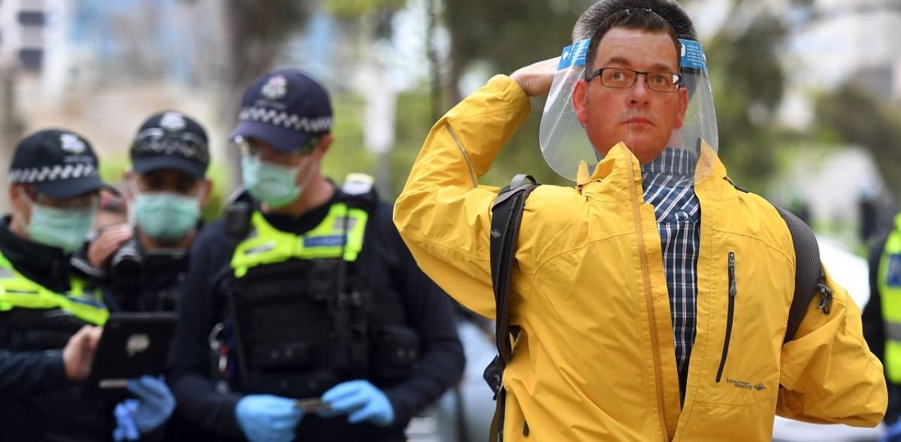 A protester (R) wears a face shield with an image of Victoria's state premier Daniel Andrews. Credit: Reuters