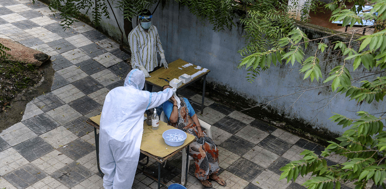 A health worker suit collects a swab sample from a woman for a Covid-19 test at a public health centre in Hyderabad. Credit: AFP Photo