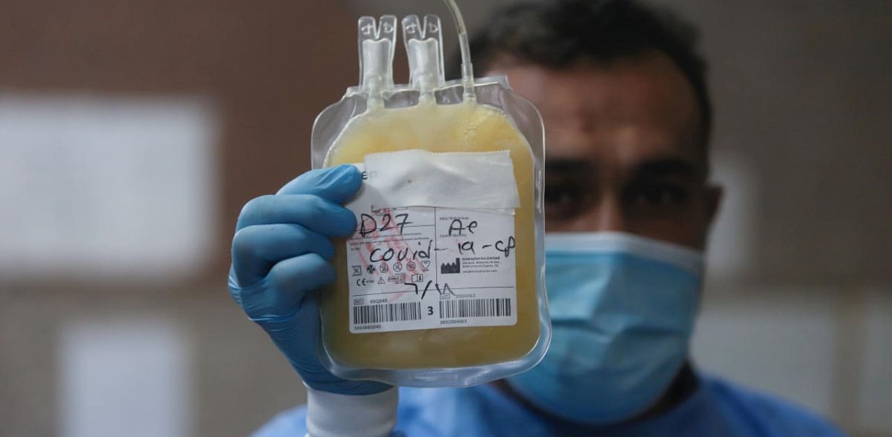 A nurse wearing a protective face mask and gloves shows blood plasma from a person who has recovered from the coronavirus disease. Credit: Reuters