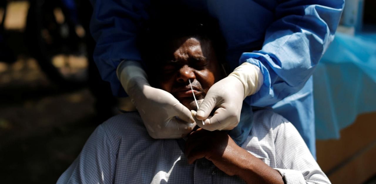 A healthcare worker wearing personal protective equipment (PPE) takes a swab from a migrant laborer for a rapid antigen test at the site of an under construction residential complex amidst a coronavirus disease outbreak in New Delhi. Credit: Reuters