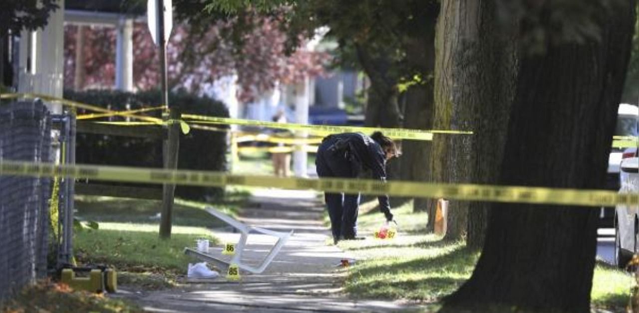A Rochester police technician picks up some items as evidence near the home where a fatal house party took place. Credit: AP/PTI Photo