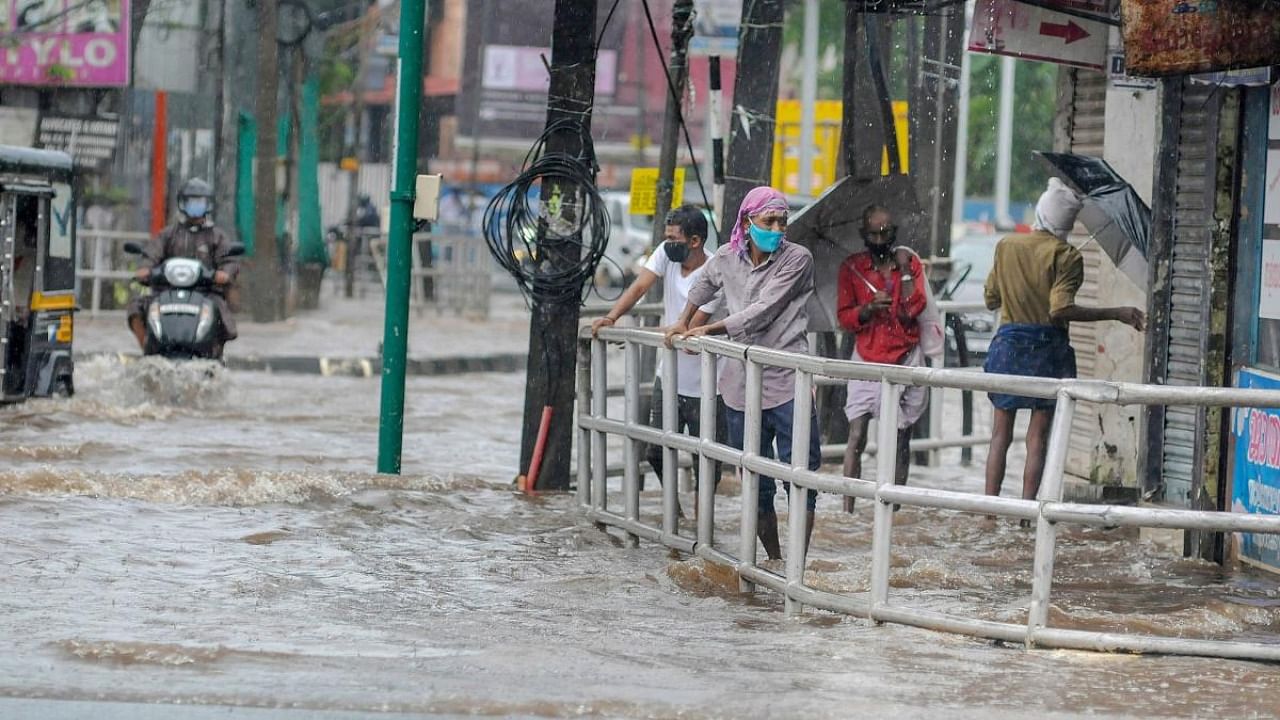 People wade through a waterlogged street after heavy rain, in Kozhikode. Representative image. Credit: PTI.