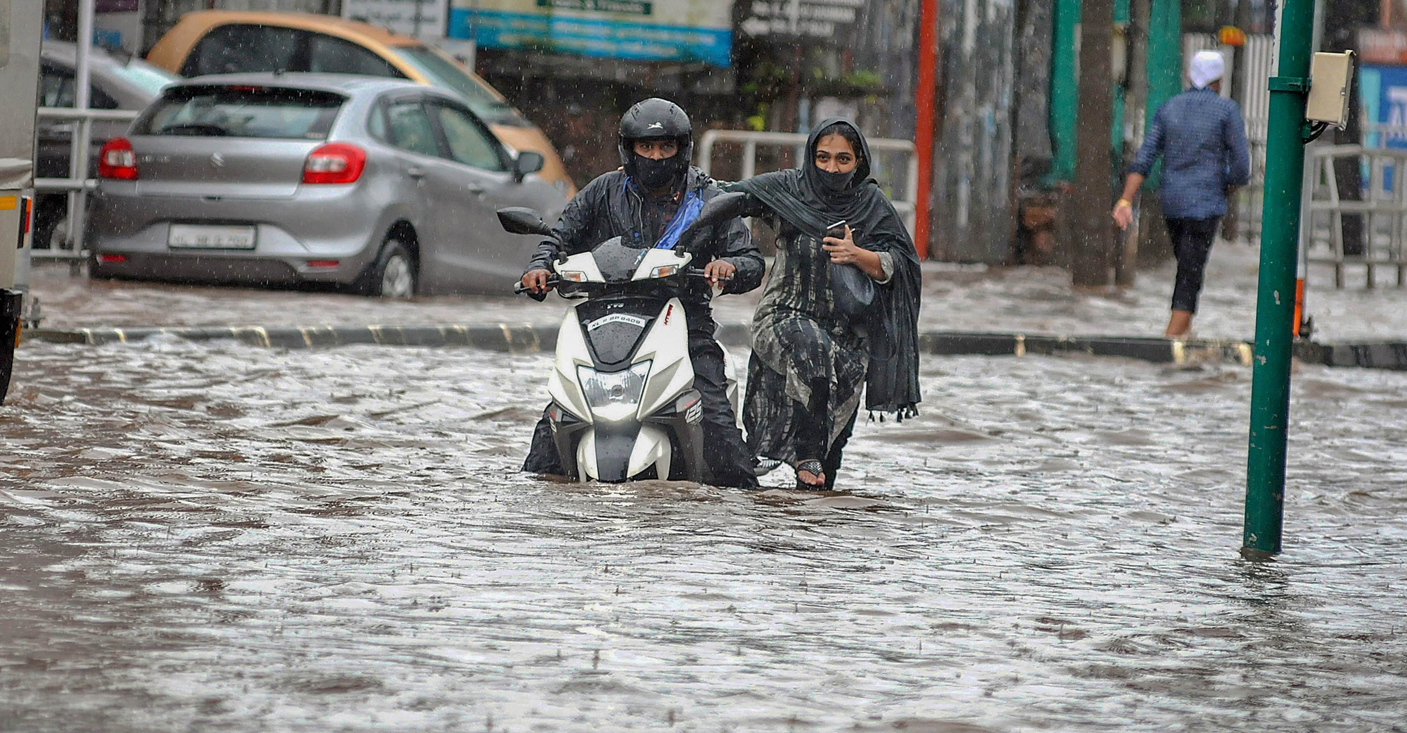 Commuters move through a waterlogged street after heavy rain. Credits: PTI Photo