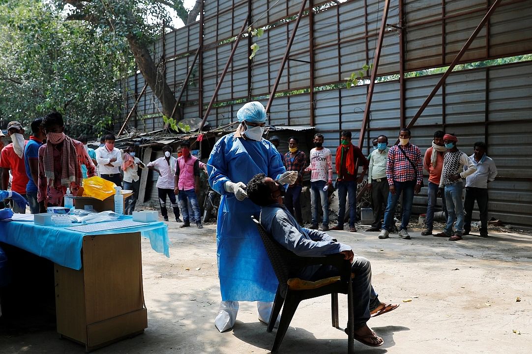 A healthcare worker wearing personal protective equipment (PPE) takes a swab from a migrant laborer. Credits: Reuters Photo