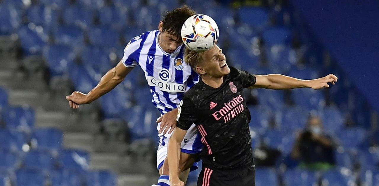 Real Madrid's Martin Odegaard jumps for the ball against Real Sociedad's Robin Le Normand. Credit: AP