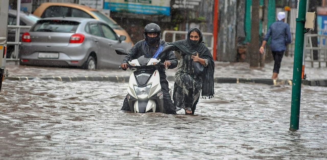 Commuters move through a waterlogged street after heavy rain. Credit: PTI