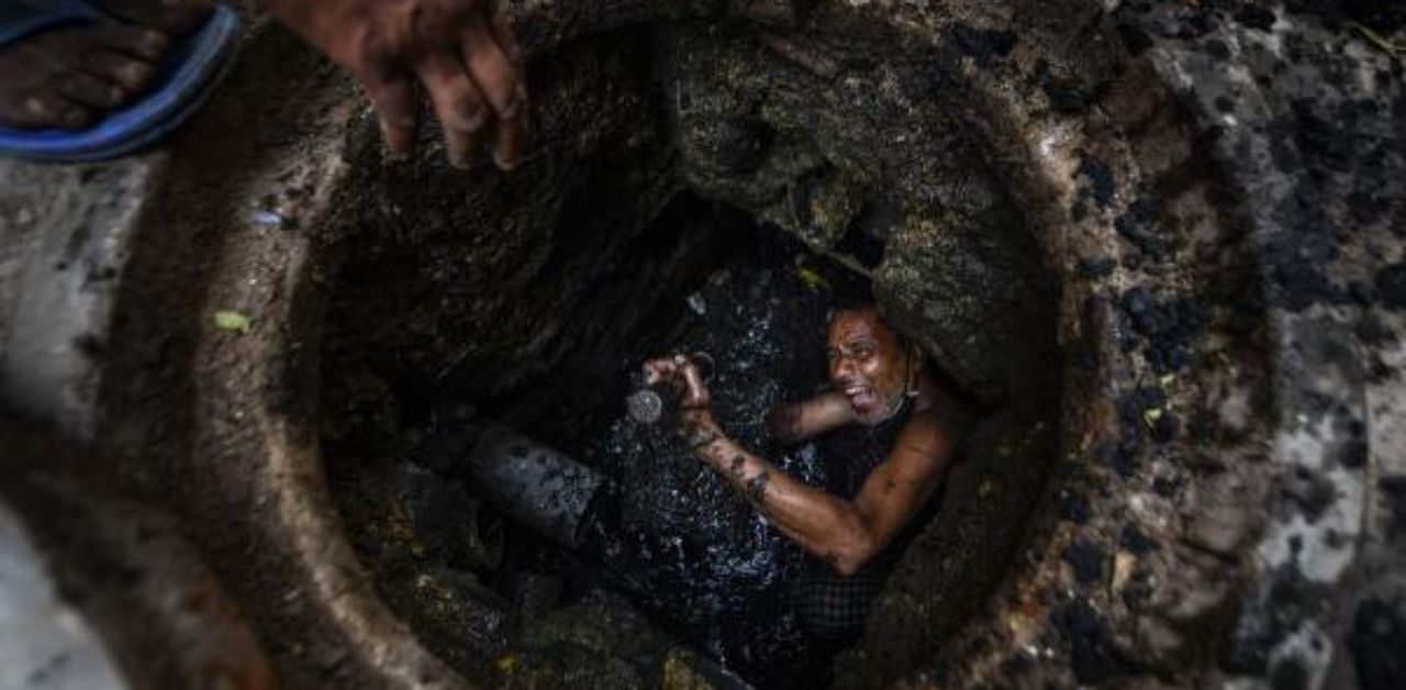 Phoolu (45), a full-time worker, shows his hands while cleaning a manhole in Ghaziabad. Credit: PTI Photo