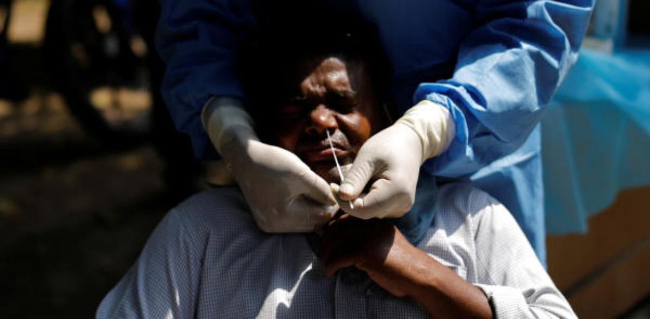 A healthcare worker wearing personal protective equipment (PPE) takes a swab from a migrant laborer for a rapid antigen test at the site of an under construction residential complex amidst a coronavirus disease. Credit: Reuters Photo