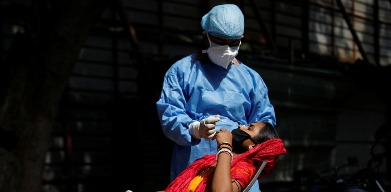 A healthcare worker wearing personal protective equipment (PPE) takes a swab from a migrant laborer for a rapid antigen test at the site of an under construction residential complex amidst a coronavirus disease (Covid-19) outbreak in New Delhi, India, September 19, 2020. Credit: REUTERS Photo