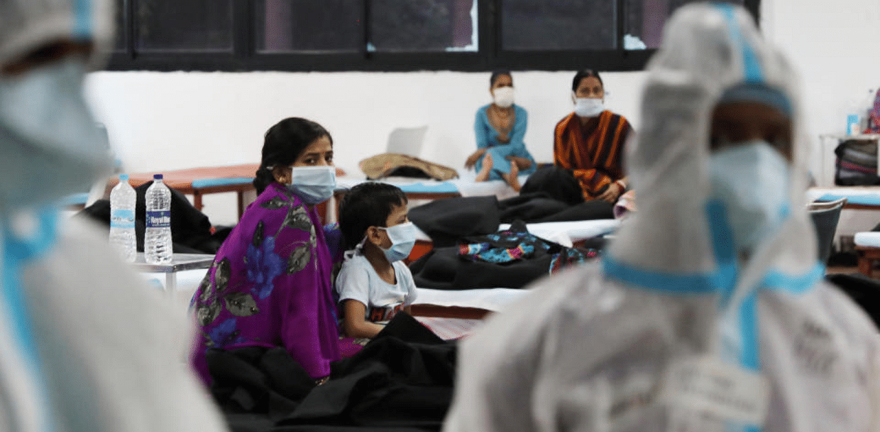 A woman sits with her child inside a quarantine centre for the coronavirus disease patients. Credit: Reuters