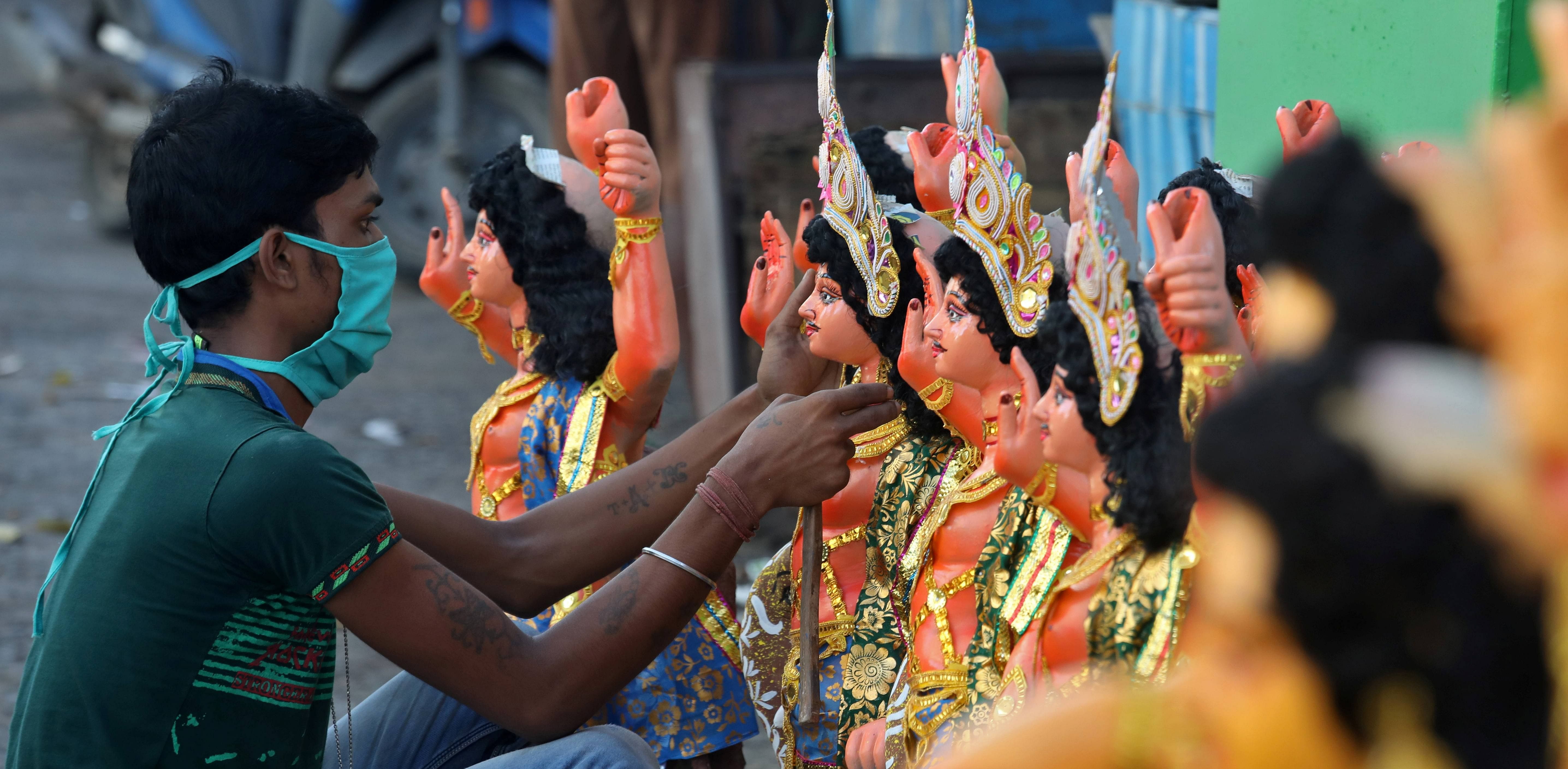 An artisan wearing a protective face mask adorns idols of Lord Vishwakarma, the Hindu deity of architecture and machinery, kept on display for sale ahead of the Vishwakarma festival. Credit: Reuters