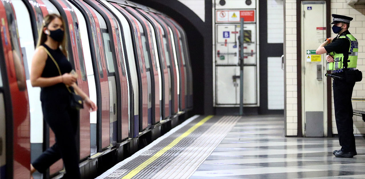 A police officer looks on as a commuter wearing a protective face mask leaves a train at Waterloo underground station during the morning rush hour, amid the coronavirus disease. Credit: Reuters Photo