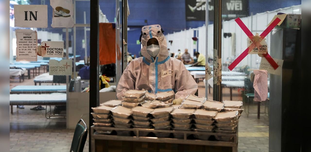 A medical health worker personal protective equipment (PPE) collects food boxes from a cart inside a quarantine centre for the coronavirus disease patients amidst the spread of the disease at an indoor sports complex in New Delhi, India, September 22, 2020. Credit: Reuters Photo