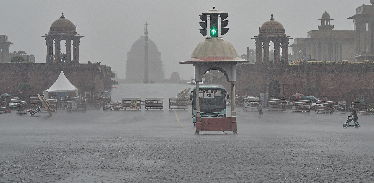 A cyclist rides across a road during rain, in New Delhi. Credit: PTI Photo