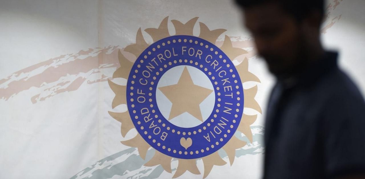 A man walks in front of the logo for the Board of Control for Cricket in India (BCCI). Credit: AFP