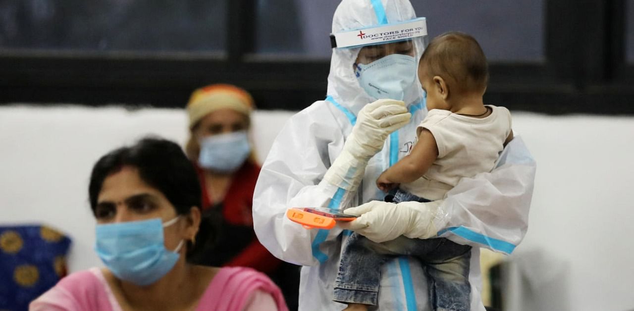 A medical worker in personal protective equipment (PPE) plays with a child of woman recovering inside a quarantine centre for the coronavirus disease patients amidst the spread of the disease at an indoor sports complex in New Delhi, India. Credit: Reuters