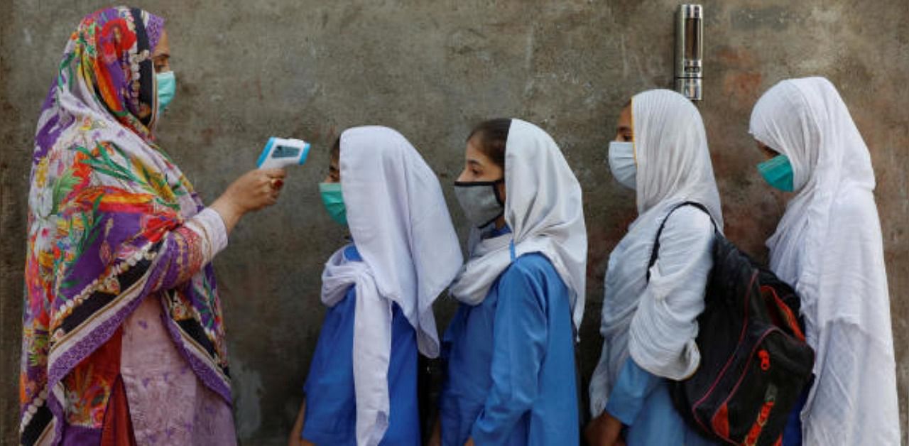 Students wear protective masks as they have their temperature checked before entering a class, after government allowed reopening of schools from grade six to eight amid the coronavirus disease (COVID-19) pandemic, in Peshawar, Pakistan. Credit: Reuters Photo