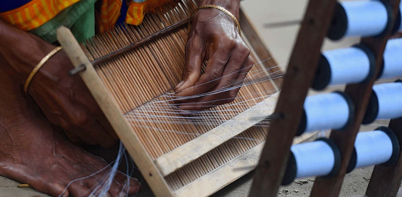 A weaver prepares threads to make fabric with a handloom in Ruhitpur on the outskirts of Dhaka. Credit: AFP Photo