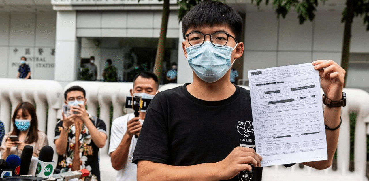 Pro-democracy activist Joshua Wong speaks to the media while holding up a bail document after leaving Central police station in Hong Kong after being arrested for unlawful assembly related to a 2019 protest against a government ban on face masks. Credit: AFP Photo