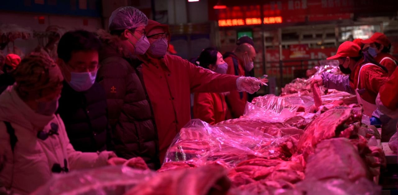 Customers wearing face masks buy meat at a wholesale market for agricultural products, as the country is hit by an outbreak of the novel coronavirus, in Beijing. Credit: Reuters