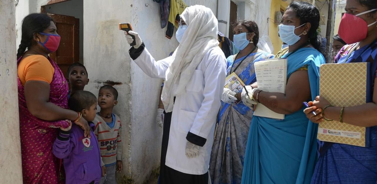 Neha Begum (C), a medical officer checks the body temperature of a resident as Accredited Social Health Activist (ASHA) workers watch during the health check-up of residents to test for the Covid-19 coronavirus at a slum area in Hyderabad. Credit: AFP